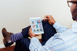 Man wearing striped shirt and socks looking at charts on a tablet