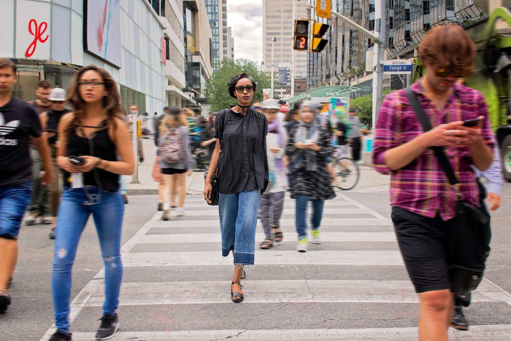 people walking across a busy intersection in downtown Toronto